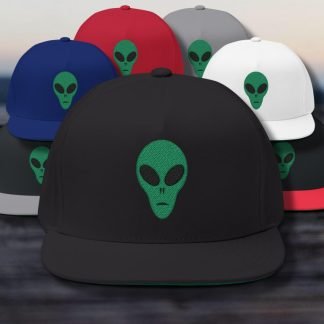 A collection of hats featuring a green alien face design. Prominently displayed in front is a black hat, surrounded by red, blue, gray, and white hats. The setting is a blurred outdoor scene.