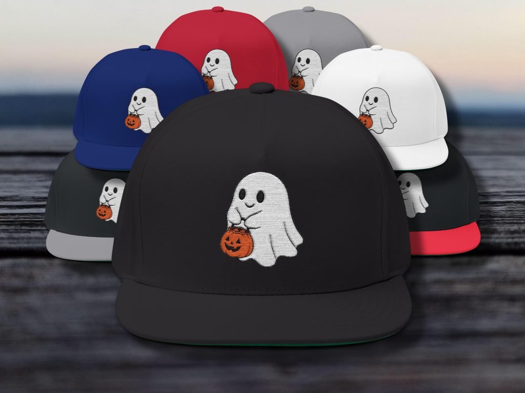 Baseball caps in various colors featuring an embroidered cute ghost holding a pumpkin design. They are arranged on a wooden surface, creating a playful, festive vibe.