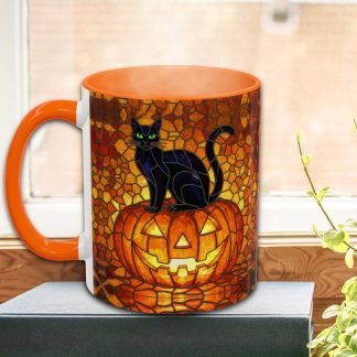Orange mug with a mosaic design featuring a black cat sitting on a carved pumpkin. It's placed on a book by a window, evoking a Halloween vibe.