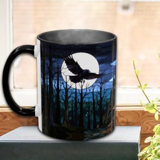 Black mug with a vivid moonlit forest scene and a flying raven. Placed on a book by a window, with steam rising and a plant beside. Mysterious and serene.