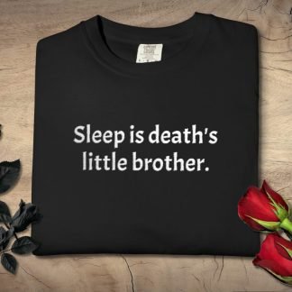Folded black t-shirt with the phrase "Sleep is death's little brother" in white text. Artistic display with black roses on left, red roses on right.