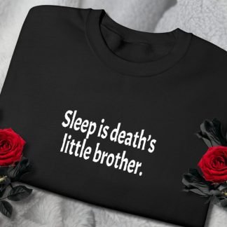 A black sweatshirt with the phrase "Sleep is death’s little brother" in white text, surrounded by two red roses on a soft grey fabric. Eerie yet elegant.