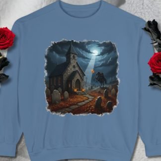 Blue sweatshirt with a spooky churchyard scene. A moonlit sky illuminates a church, graves, and a headless horseman holding a glowing pumpkin. Moody and eerie.