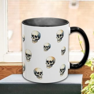 A white mug with a black handle displays a pattern of skull illustrations, emitting steam. It rests on a book near a window and a plant, conveying a cozy Halloween vibe.